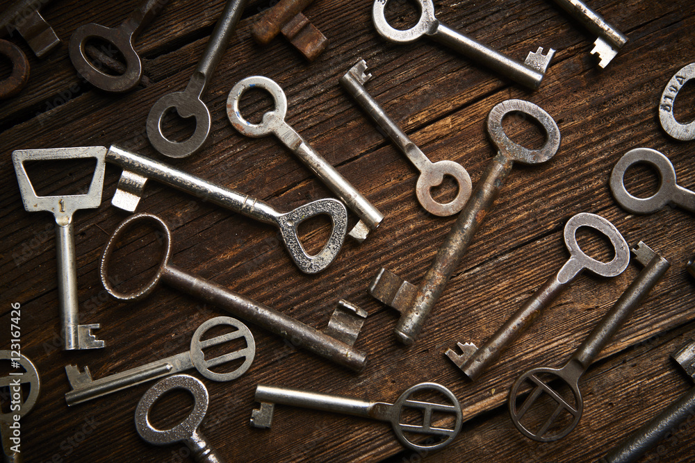 many different keys on brown wooden background.
many different keys on brown wooden background.
