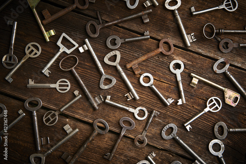 many different keys on brown wooden background. 
