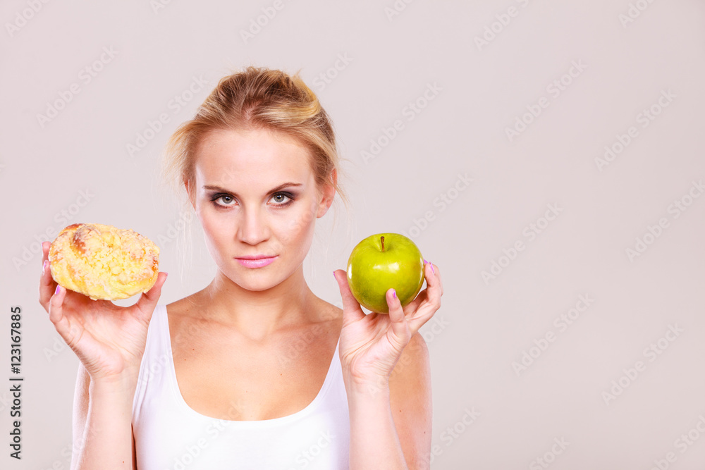 Woman holds cake and fruit in hand choosing Woman holds cake and fruit in hand choosing