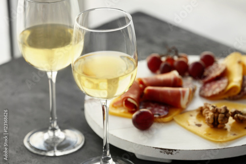 Glasses with white wine and tasty snacks on a table