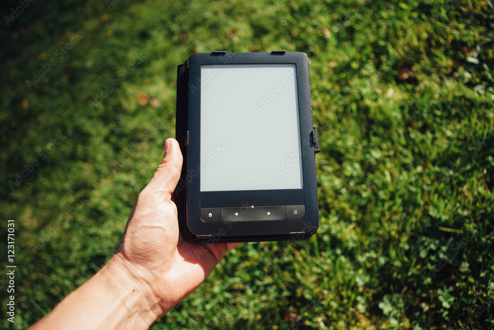 e-Book reader in hand, green grass background