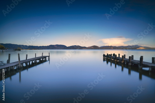 Two Wooden pier or jetty and on a blue lake sunset