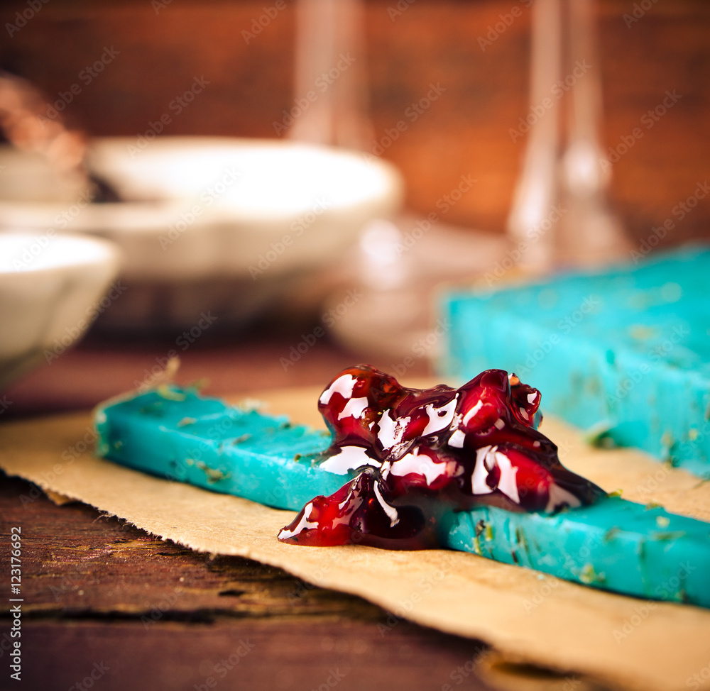 Blue pesto cheese with herbs, pomegranate jam and sauces on wooden rustic background Blue pesto cheese with herbs, pomegranate jam and sauces on wooden rustic background
