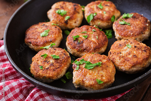 Juicy delicious meat cutlets in pan on a wooden table.