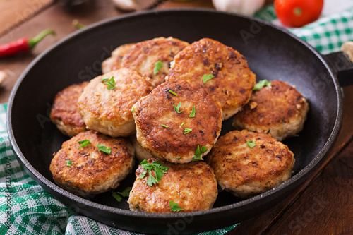 Juicy delicious meat cutlets in pan on a wooden table.