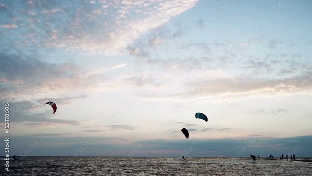 Kitesurfing. Silhouettes of four surfers riding on boards on the surface of waves and jumping with kite at sunset. Azov sea. HD Kitesurfing. Silhouettes of four surfers riding on boards on the surface of waves and jumping with kite at sunset. Azov sea. HD