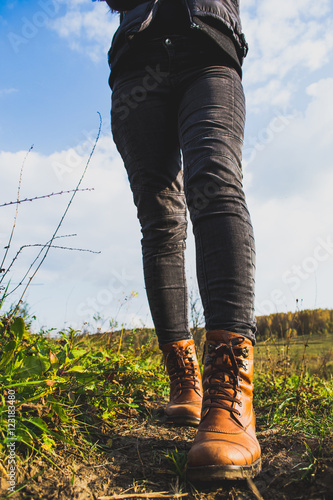 Female legs shod in Hiking boots on the forest background