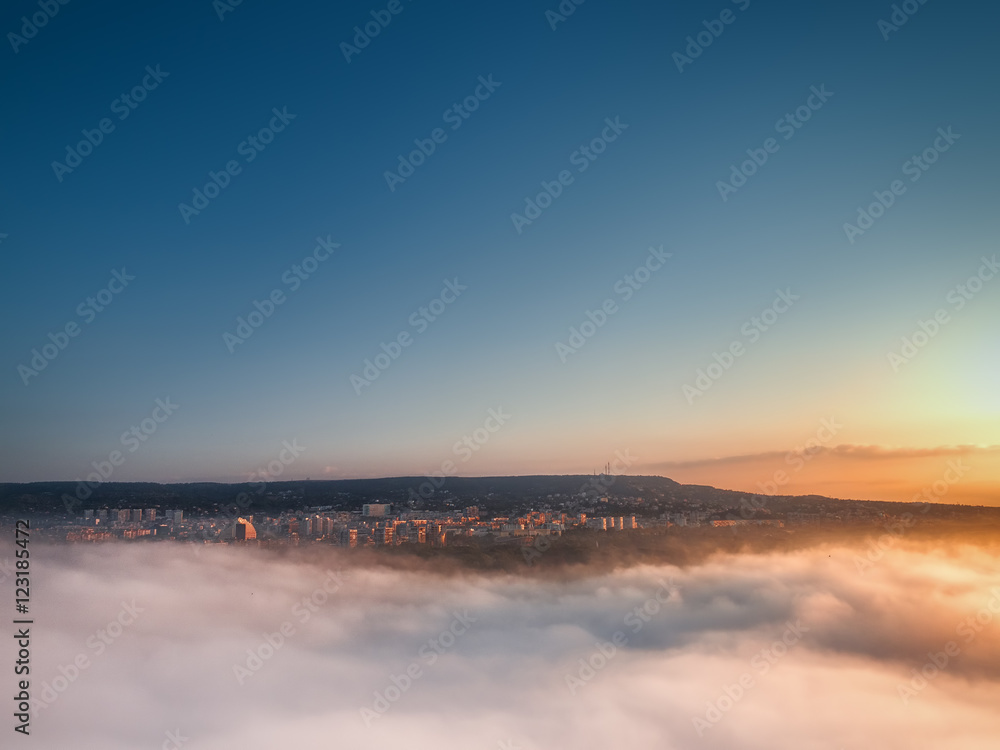 Flying above the clouds. Sunrise over the city