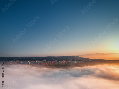 Flying above the clouds. Sunrise over the city