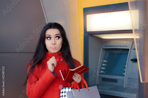 Funny Shopping Woman Holding a Penny in front of an ATM photo