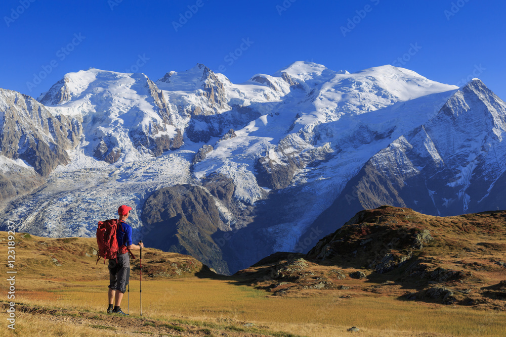 Hiker in a meadow looking towards Mont Blanc, during his hike of the Tour du Mont Blanc.