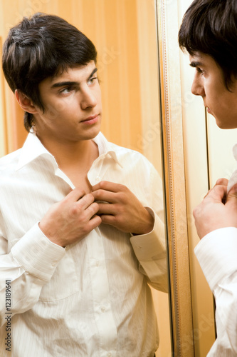 Portrait of handsome man getting dressed in front of mirror