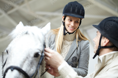 Image of young woman sitting on the horse and looking at instructor