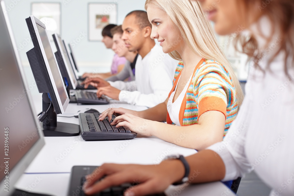 Fototapeta premium Selective focus of a girl working with computer among other students