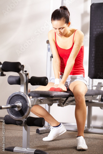 A young girl sitting on exercise machine in gym