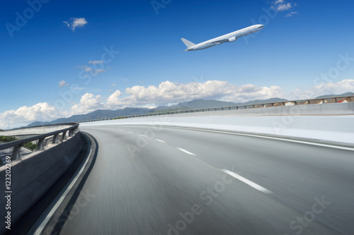 Highway overpass motion blur with blue sky and aeroplane . © jamesteohart