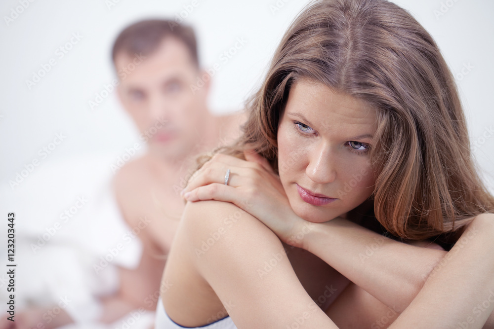Displeased woman in bed with her husband Displeased woman in bed with her husband