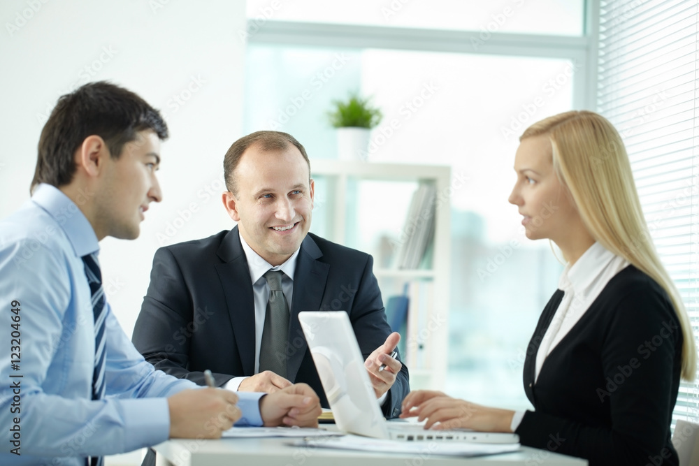 Three office workers discussing business issues in board room Three office workers discussing business issues in board room