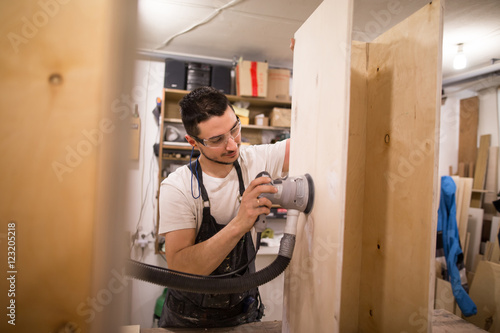 Obraz na płótnie man polishes boards. carpenter with sander