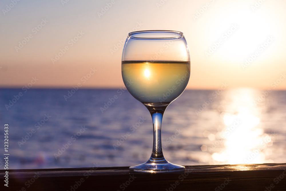 Glass of white wine at sunset on the sea.