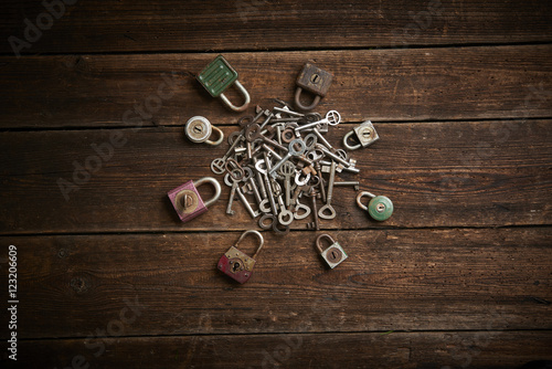 Group of old rusty padlocks with pile of keys on brown wooden table 