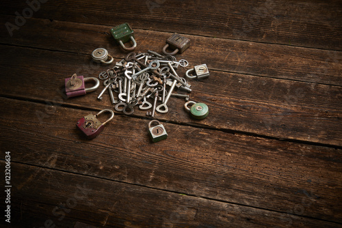 Group of old rusty padlocks with pile of keys on brown wooden table 