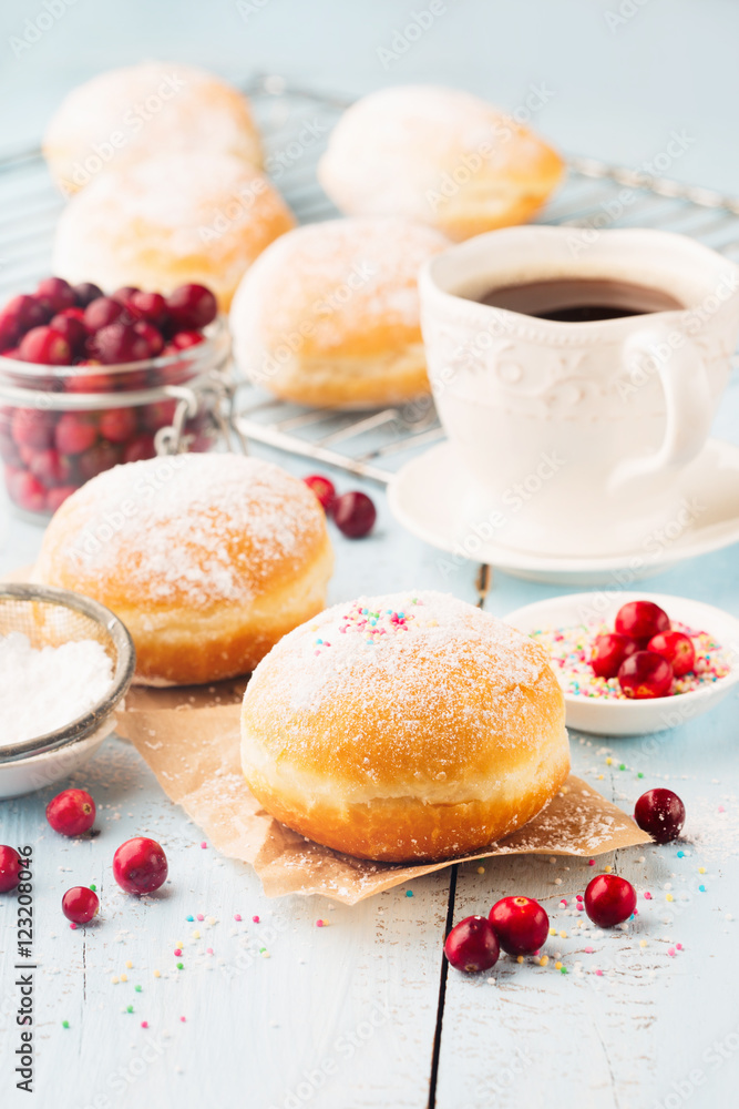 Delicious freshly baked doughnuts with powdered sugar and cup of coffee on blue rustic wooden background. Delicious freshly baked doughnuts with powdered sugar and cup of coffee on blue rustic wooden background.