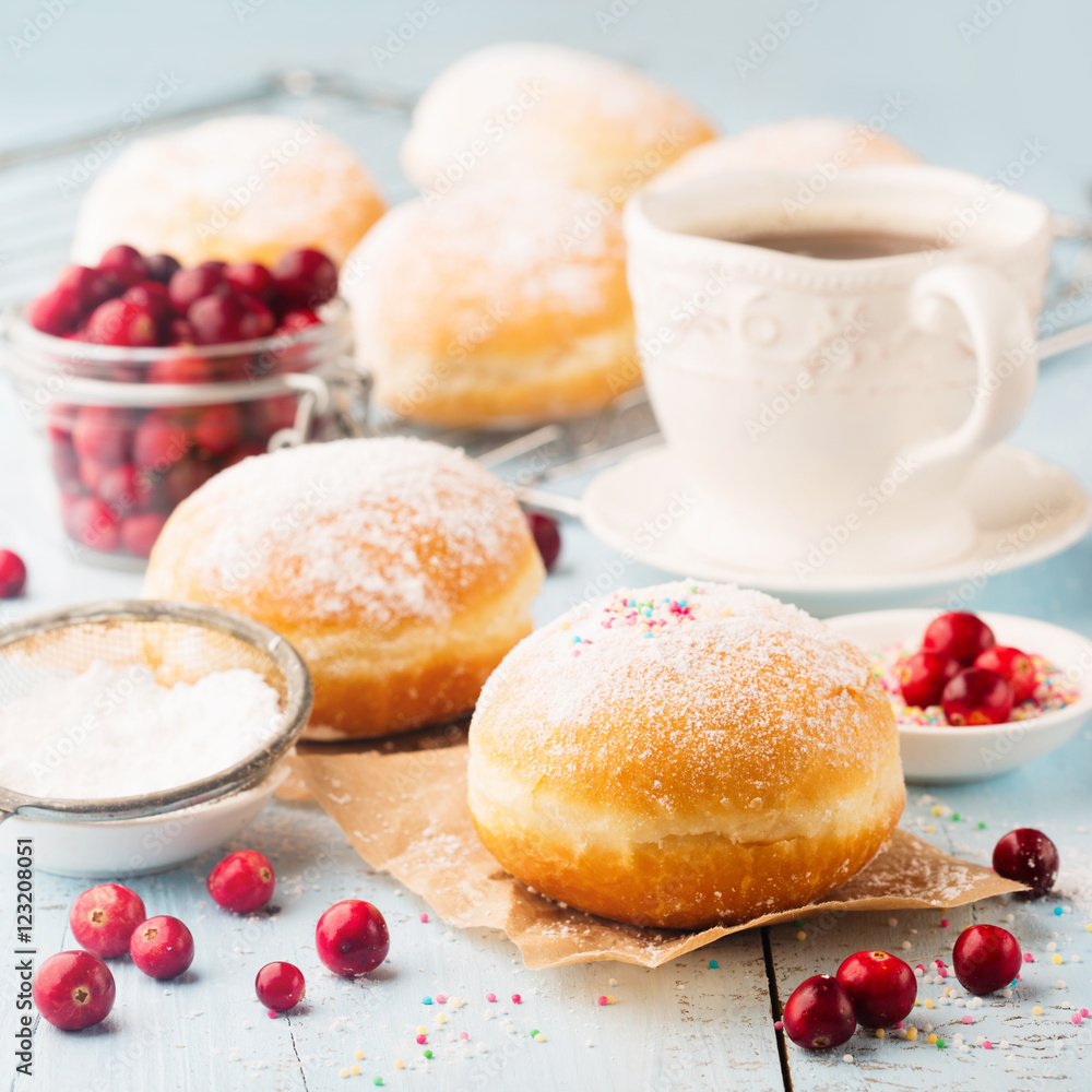 Delicious freshly baked doughnuts with powdered sugar and cup of coffee on blue rustic wooden background. Breakfast concept Delicious freshly baked doughnuts with powdered sugar and cup of coffee on blue rustic wooden background. Breakfast concept