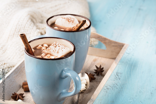Blue Cups of hot Chocolate drink with Marshmallows and cinnamon on blue wooden background. Winter time. Holiday concept