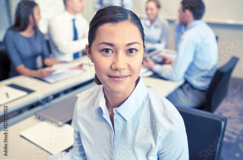 group of smiling businesspeople meeting in office