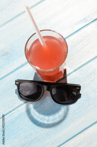 creative summer smile. red drink in glass on blue summer table