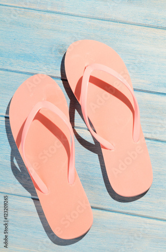 pink flip flops on blue wooden table with sunlight