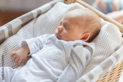 Newborn baby boy lying in a basket and sleeps