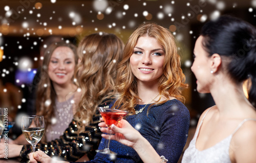 happy women with drinks at night club over snow