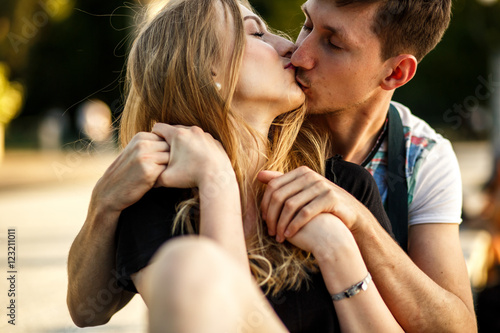 Tender kiss of young couple sitting in each other hugs