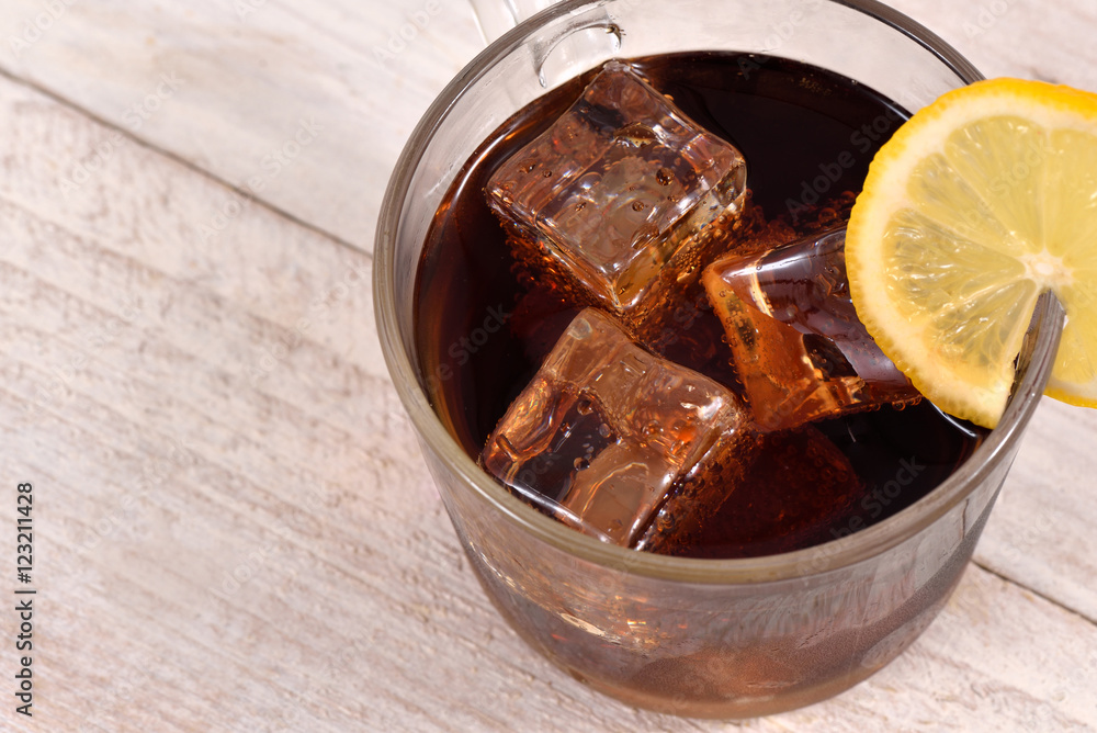 Cola drink with ice cube and lemon slice on white rustic wood background top view Cola drink with ice cube and lemon slice on white rustic wood background top view