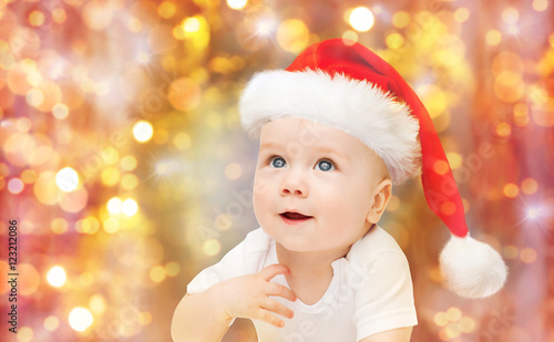 baby boy in christmas santa hat over blue lights
