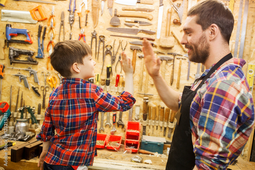 father and little son making high five at workshop - obrazy, fototapety, plakaty 