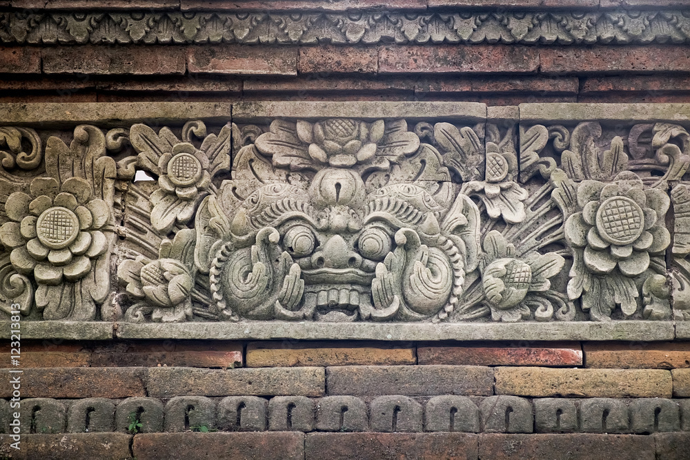 Close up view of carved stone fence of traditional Hindu temple with demon guard in Indonesia, Bali.