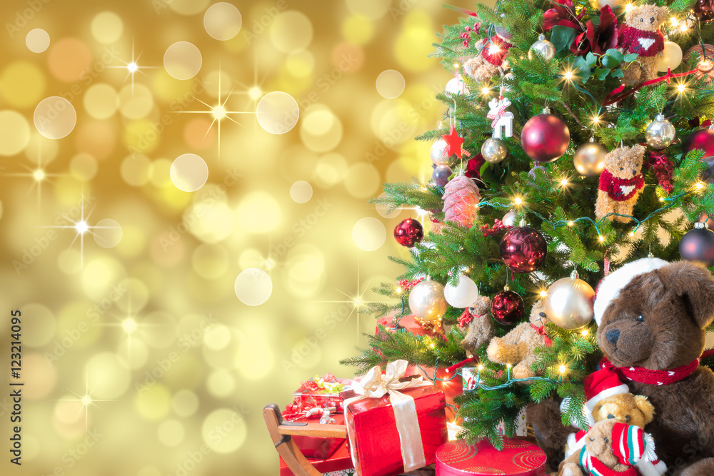 Gold Christmas background with defocused lights, decorated Christmas tree, red gift box and teddy bears. Gold Christmas background with defocused lights, decorated Christmas tree, red gift box and teddy bears.