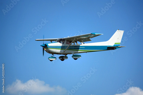 Light general aviation aircraft on final with cloud sky landing configuration