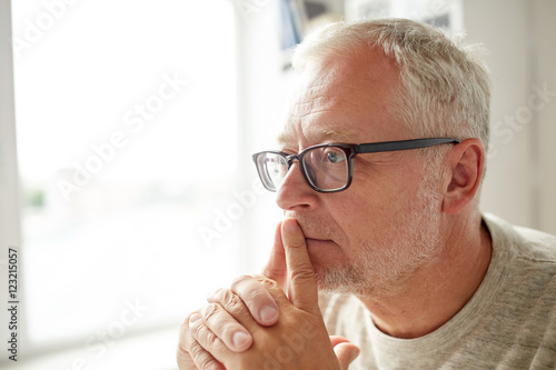 close up of senior man in glasses thinking