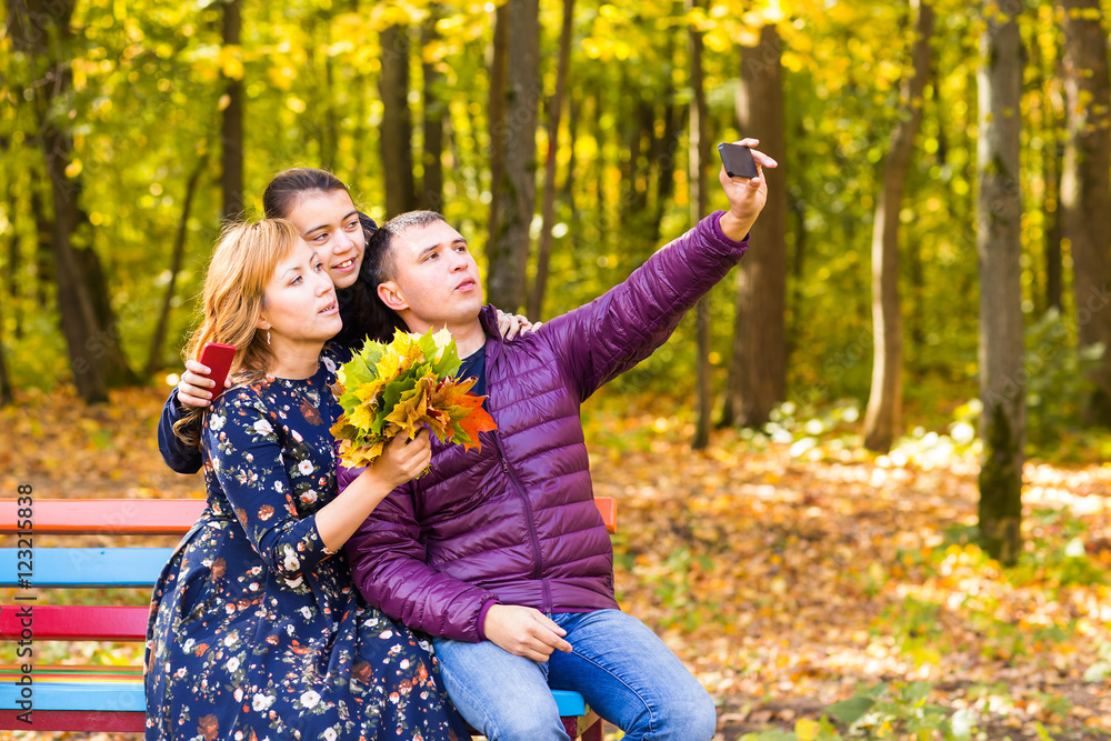 Fototapeta premium family, childhood, season, technology and people concept - happy family photographing in autumn park