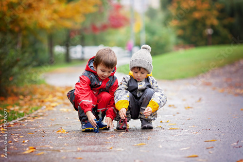 Two children, playing with toys in the park on a rainy day