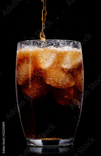 Glass of cola with ice on black background.