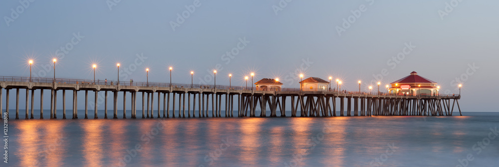 Naklejka premium Panorama of Huntington beach pier lit up by street lights at dusk 