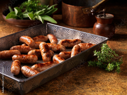 Christmas, celebration food, classic cocktail sausage selection, in baking tray, fresh thyme and sage photo