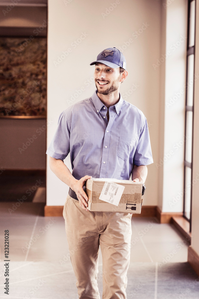 Delivery man carrying package in office Stock Photo | Adobe Stock