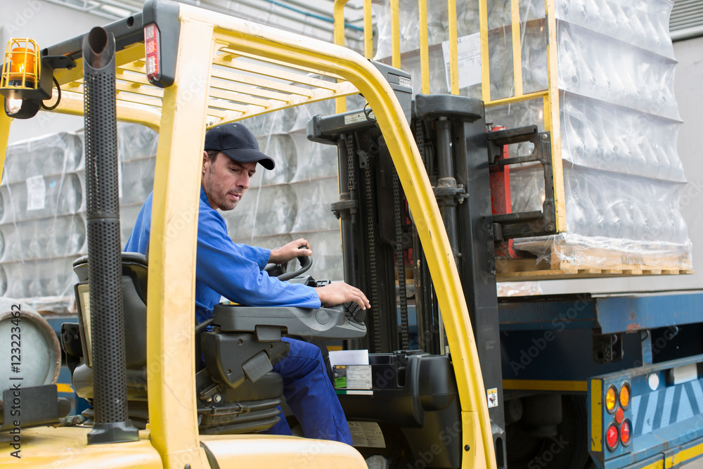 Forklift driver loading pallet onto truck at packaging factory Stock ...