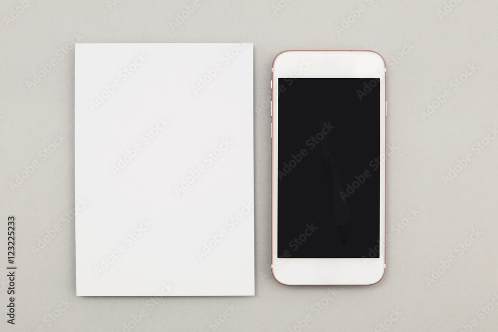Blank white postcard flyer alongside a smartphone with a blank screen Blank white postcard flyer alongside a smartphone with a blank screen